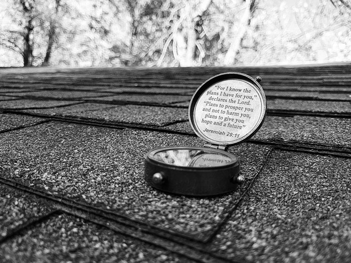 A black and white photo of a compass sitting on a roof.