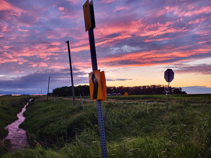 A photo of a road sign during a colorful sunset.