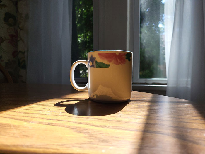 A coffee cup resting on a table during the morning.