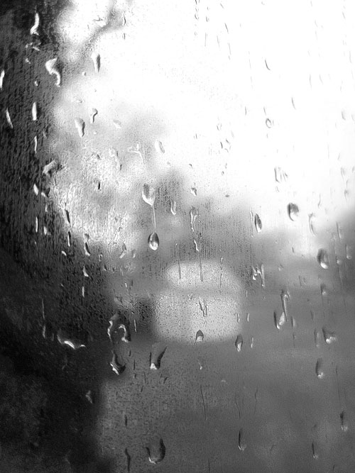 A black and white photo of rain drops on a window.