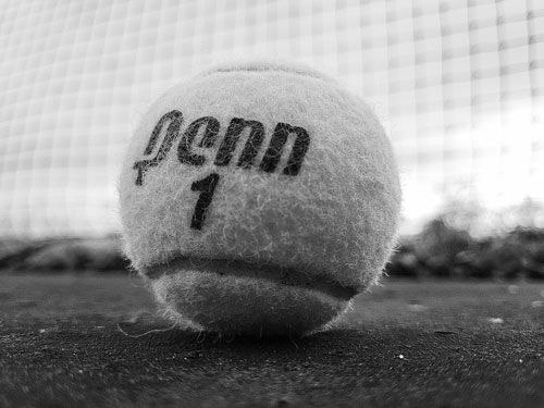 A tennis ball sitting on the ground in a tennis court.